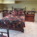A bed with a metal frame and colorful bedspread.